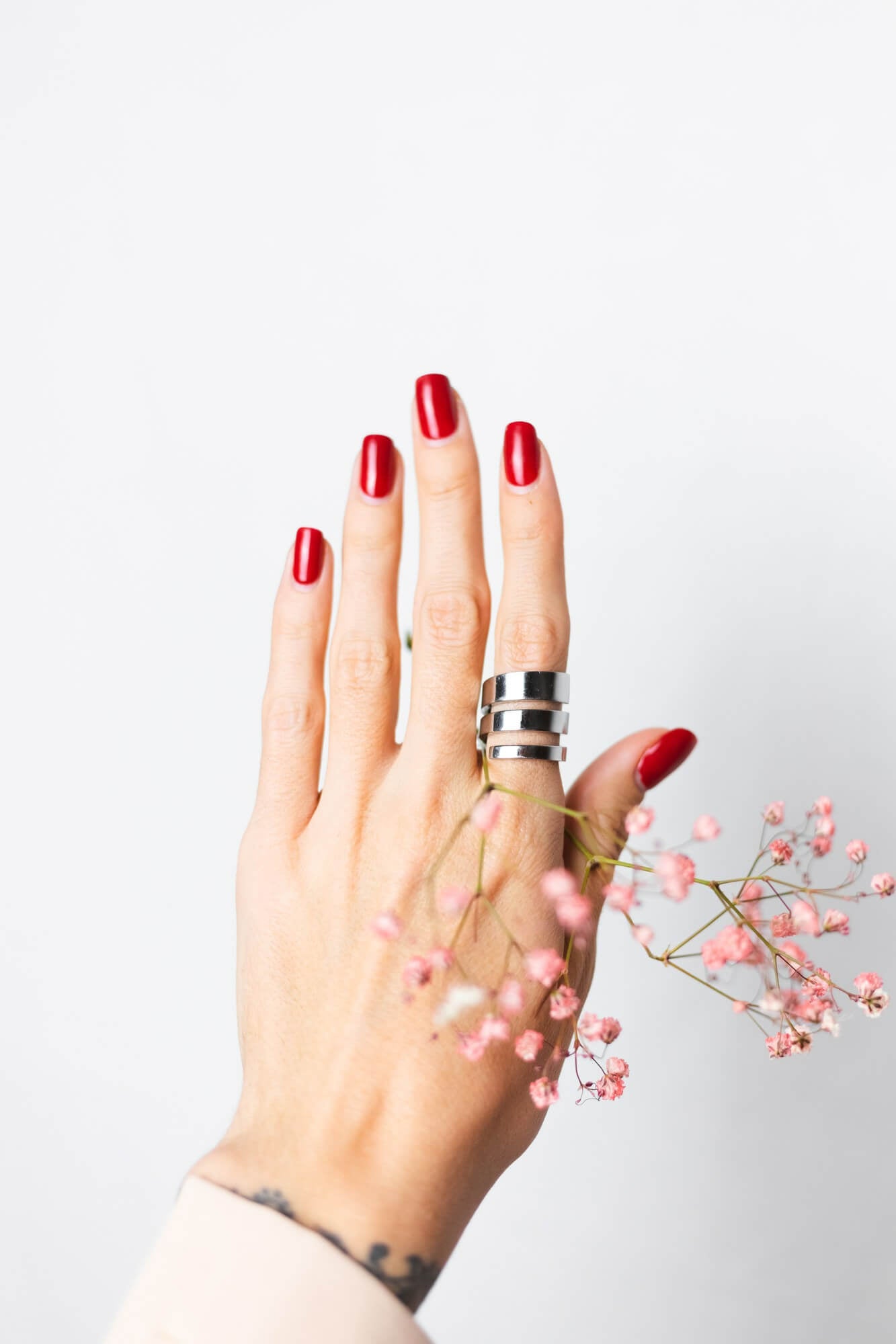 An illustration of a hand, nails done with red nail polish, the hand hold a flower