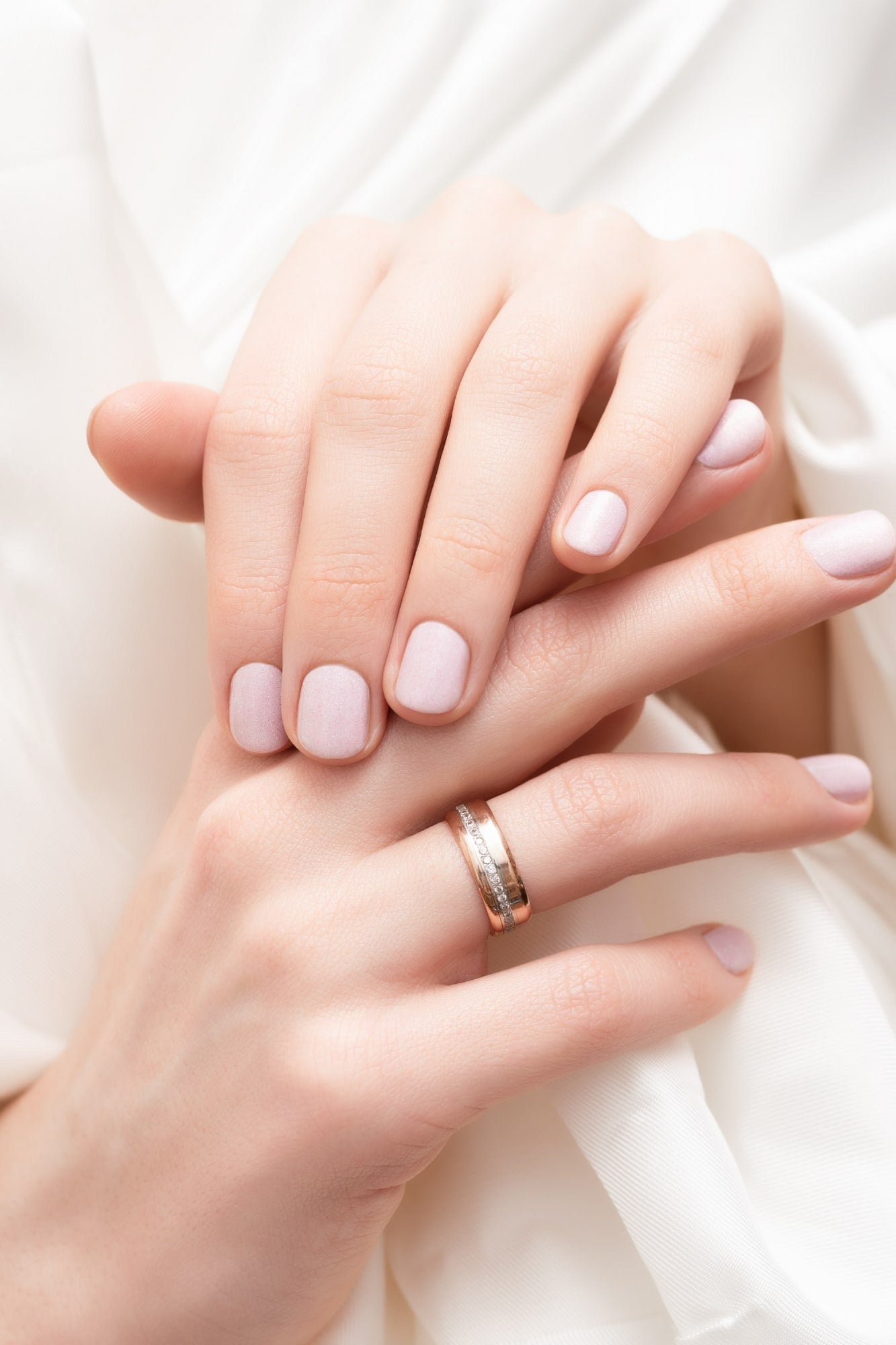 Nails with beige nail polish behind the "contact us" text